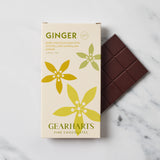 A boxed ginger dark chocolate bar from Gearharts Fine Chocolates sits on a light marble surface next to a partially unwrapped dark chocolate bar. The box is cream-colored with green and yellow floral illustrations and reads 'GINGER' and 'GEARHARTS FINE CHOCOLATES.