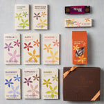 An assortment of Gearharts Gourmet chocolate and coffee products arranged on a light gray background, including various boxed toffees, caramels, pecans, blueberries, and a large brown gift box.