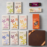 An assortment of Gearharts Gourmet chocolate and coffee products arranged on a light gray background, including various boxed toffees, caramels, pecans, blueberries, and a large brown gift box.